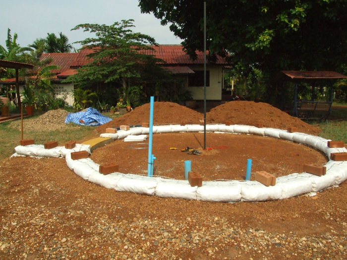 Первый ряд мешков с гравием уложен в круг, чтобы построить дом из земли